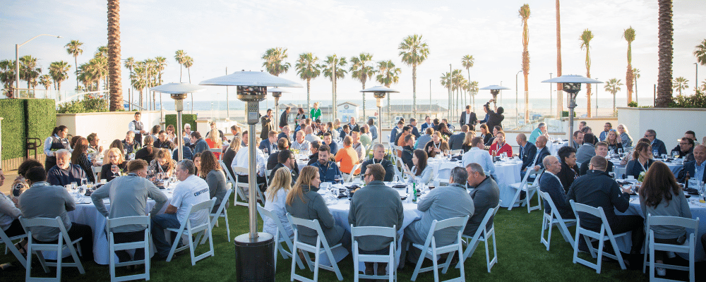 group of event attendees networking during a conference dinner with palm trees