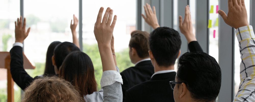 group of event attendees raising their hand during a conference