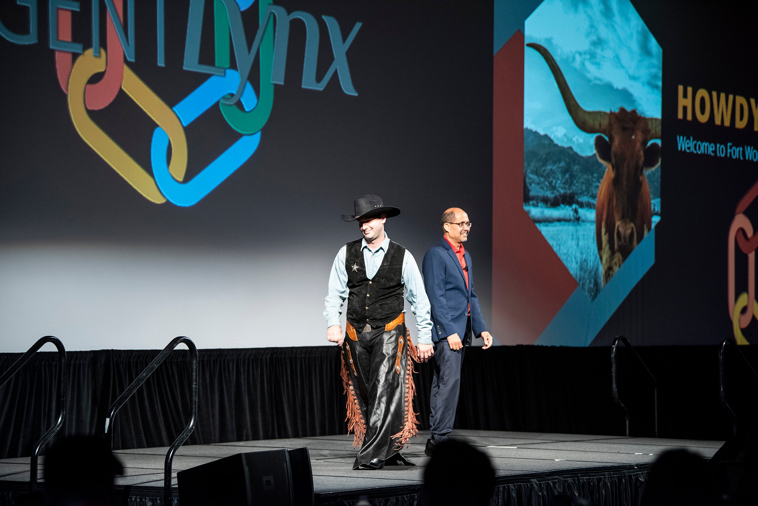 Conference main stage with two speakers, one in a cowboy costume