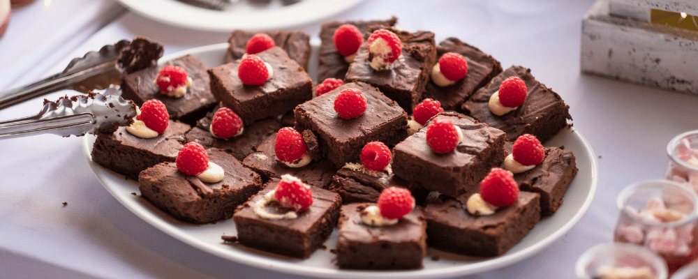 plate of dark chocolate brownies with raspberries on top for dessert