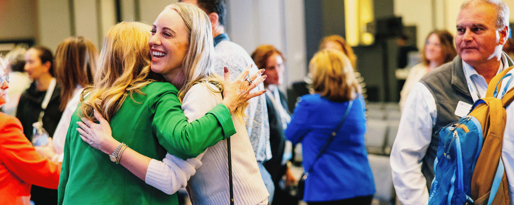 two conference attendees hugging one another
