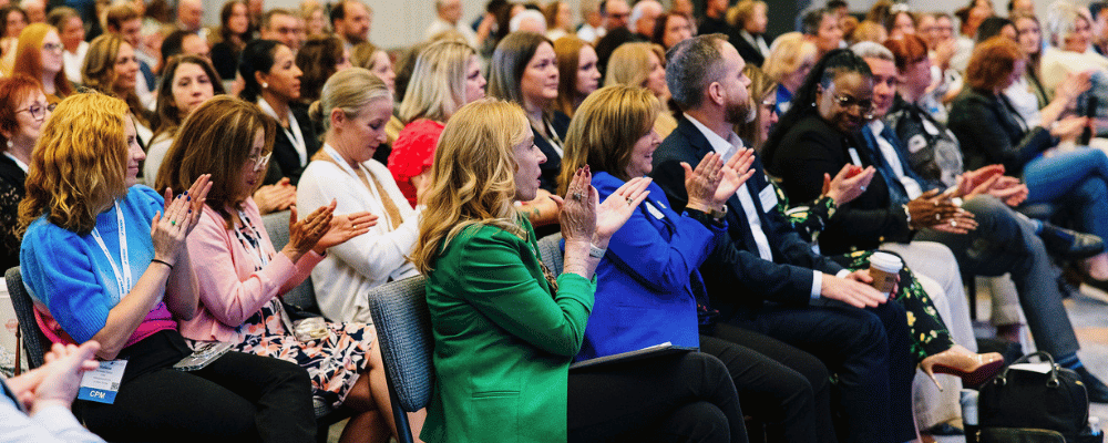 group of conference attendees clapping for a presentation