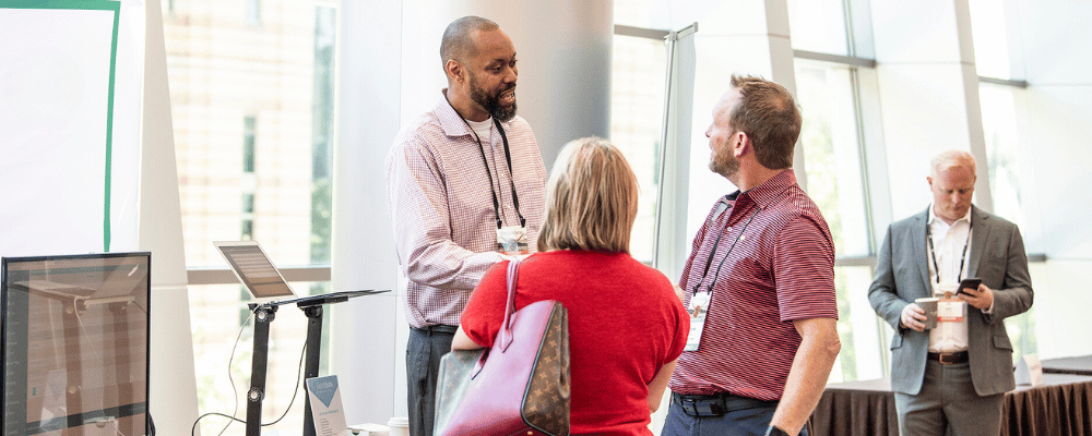 two attendees networking with a sponsor at a corporate event