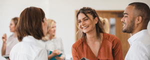 smiling woman shaking hands with a man and woman at an event