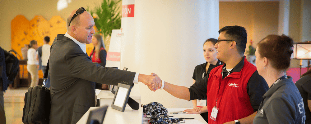 attendee shaking hands with the event registration staff during conference check-in