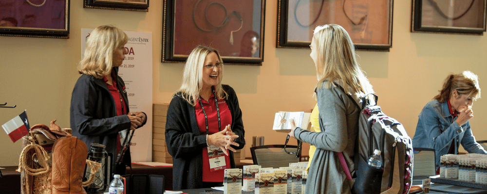 two event registration staff checking in an attendee at a conference