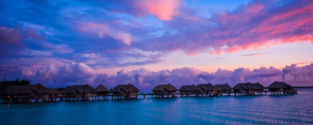 hotel huts at a resort in bora bora during sunset
