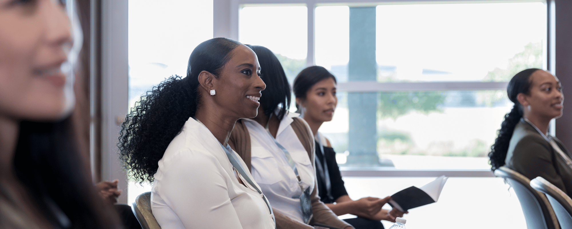 Woman listens to keynote speech at conference with other group of women