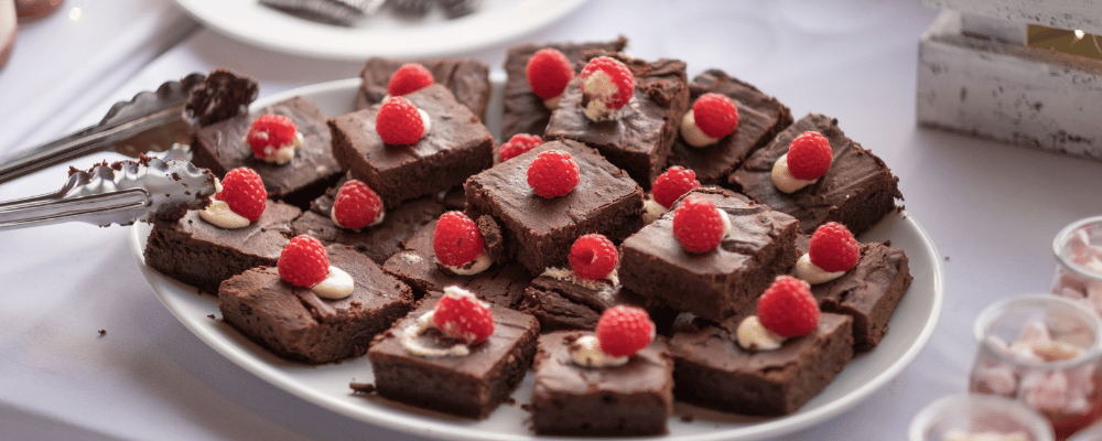 tray of brownies with raspberries on top at a corporate event buffet table