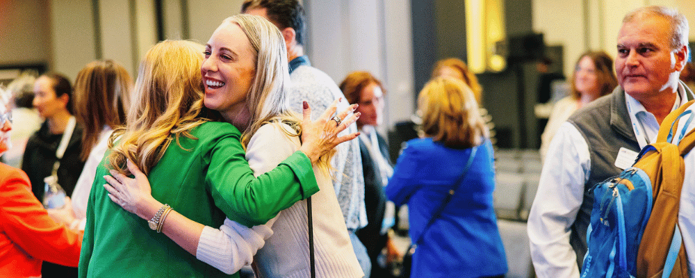 two attendees hugging during a conference
