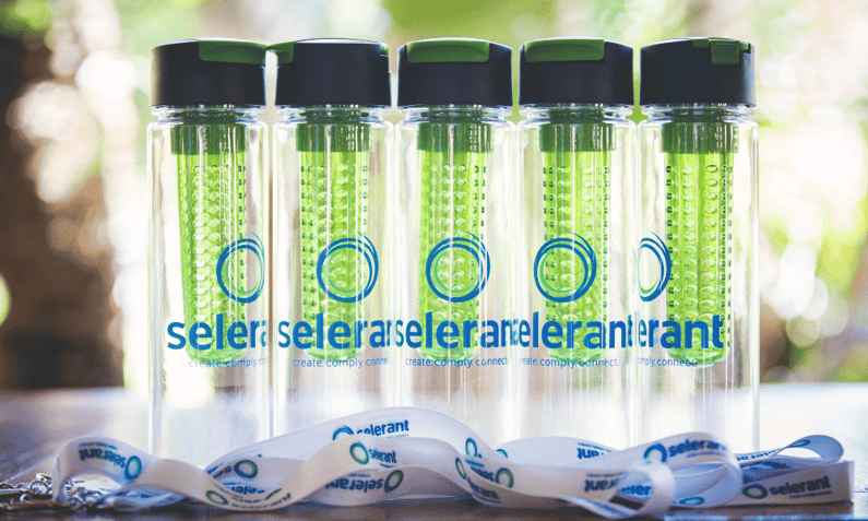 five clear reusable water bottles sitting with event name badge lanyards with a green event logo on each