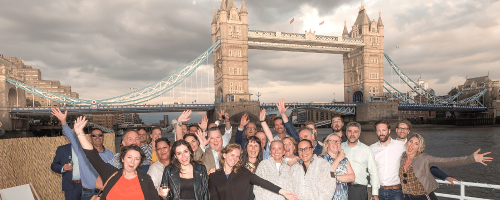 group of event attendees posing in front of london bridge during a corporate event