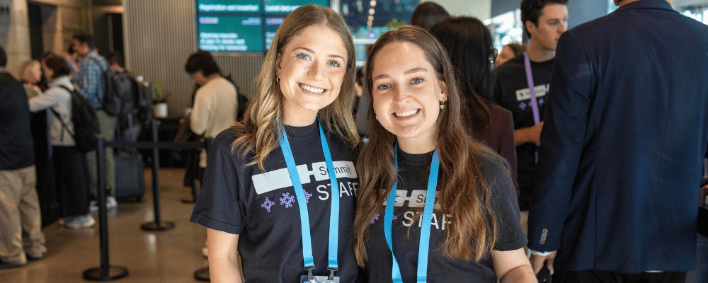 two attendees smiling during a conference presentation