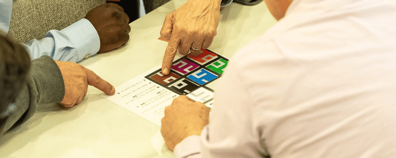 group surrounding a table pointing at cards to find a correct match