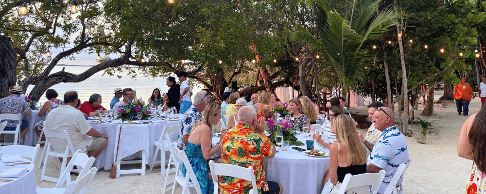 group of incentive trip attendees eating dinner on a beach