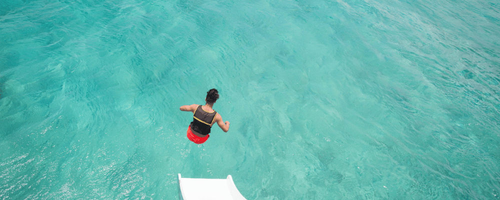 man jumping off boat into clear ocean water experiencing the benefits of incentive travel