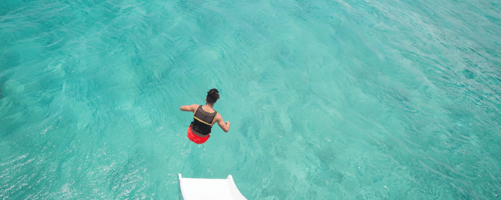 man jumping into the water from a water slide during a sales incentive trip