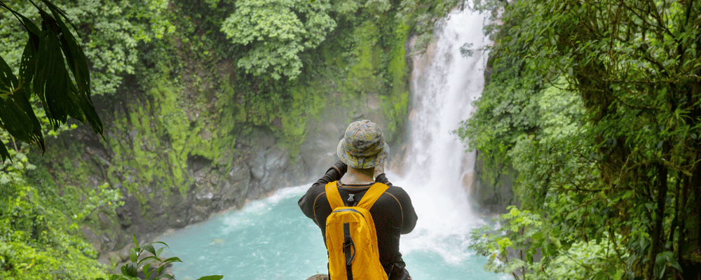 man taking photo of waterfall in costa rica