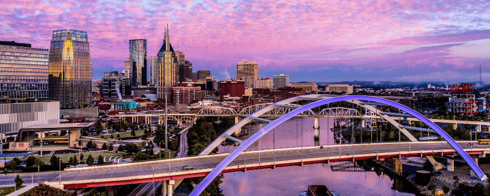 nashville skyline with bridge in the foreground and sunset behind it