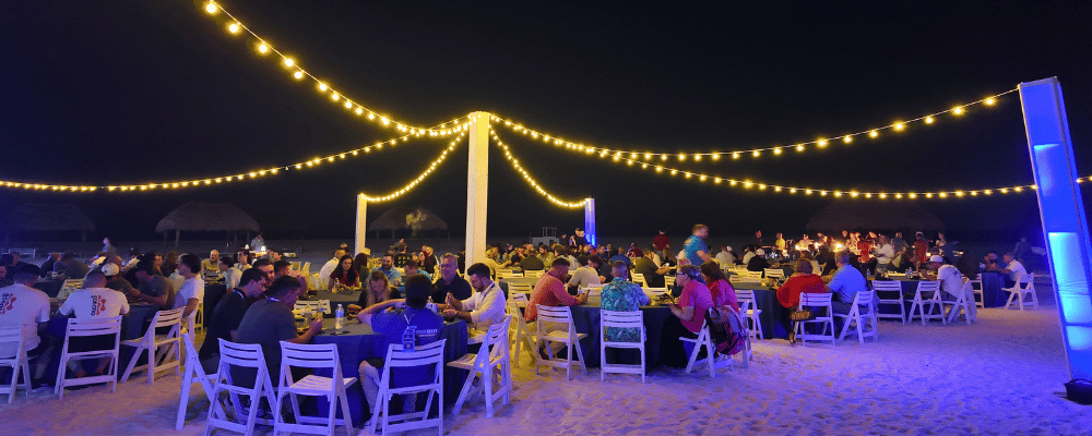 group of attendees having dinner on the beach during a conference