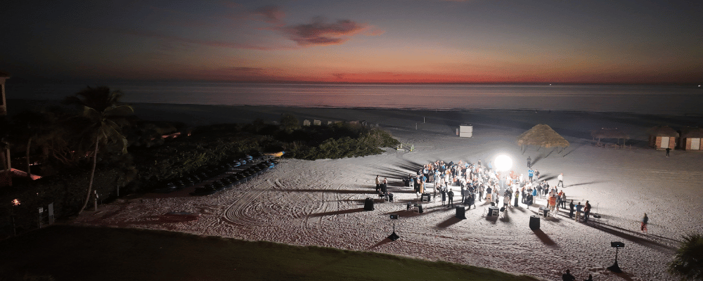 group of attendees networking on the beach during a conference