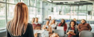 Woman presenting to an audience with sales kickoff meeting theme presentation