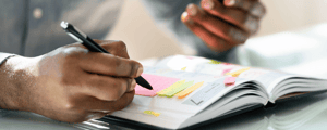 man holding pen prepping agenda for a franchise conference with a planner and sticky notes