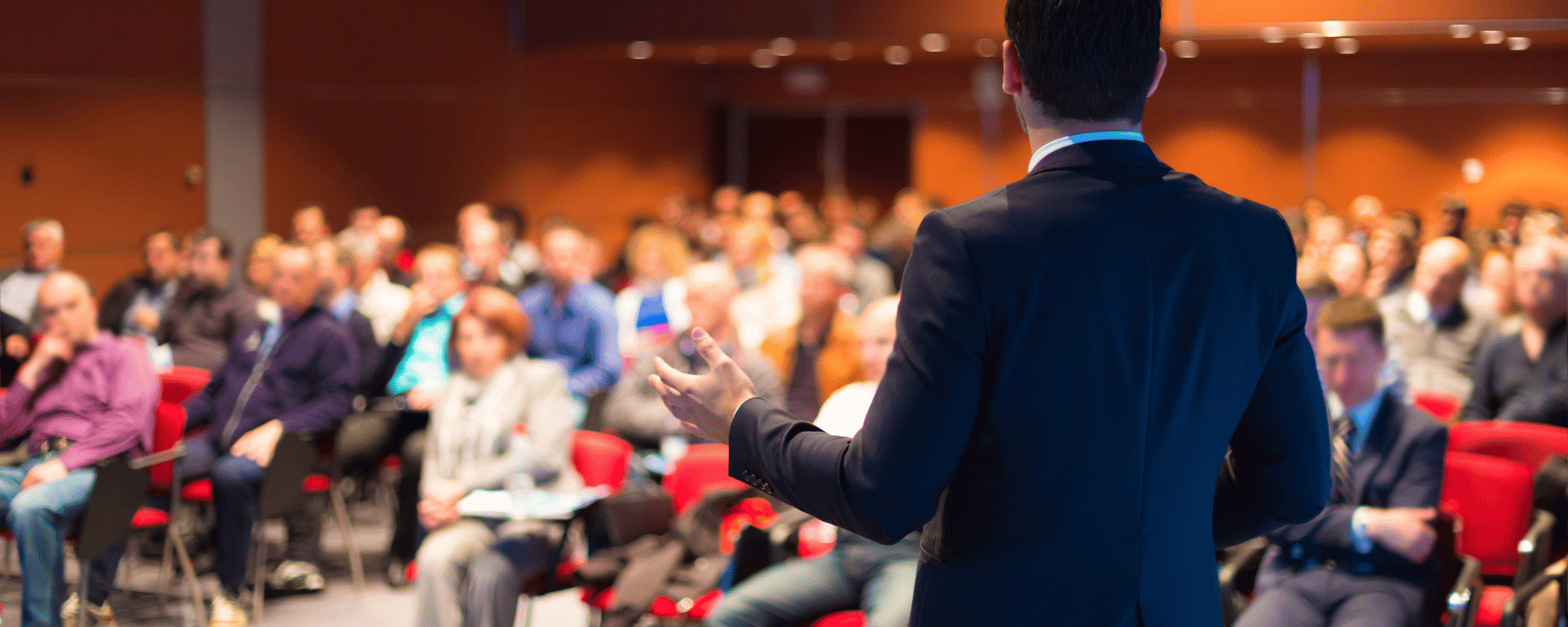 A keynote speaker giving a motivational speech to a large audience