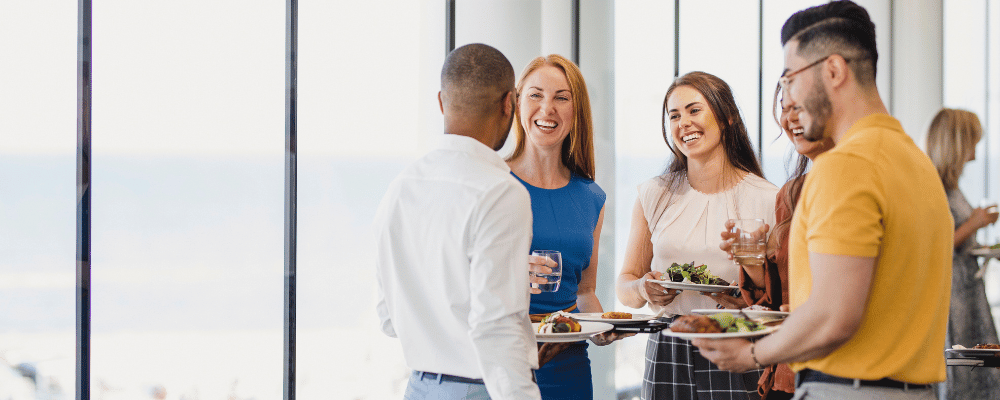 five attendees networking with food on plates at an event