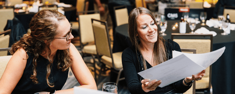two employees looking at paperwork for a conference
